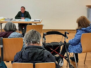 Beuscher hören bem Redener zu