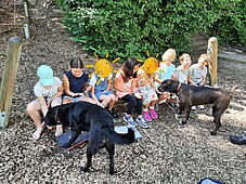 Einiger Kinder geben zwei Hunden der Hundestaffel mit ausgetreckten Händen Leckerli
