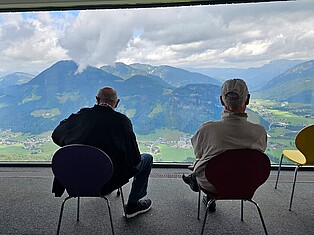 Teilnehmer sitzen im Jakobskreuz und genießen die Aussicht auf das Bergpanorama
