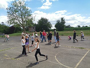 Die Kinder spielen Bewegungsspiele auf dem Schulhof