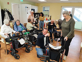 Senioren sitzen auf Stühlen und lauschen Vortrag