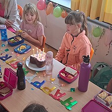 Foto eines Geburtstagskindes am Tisch. Vor dem Kind steht eine Torte mit sieben Kerzen