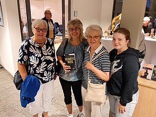 Vier Frauen, eine Frau hält das Buch "Henrys Weg" in der Hand