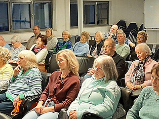 BesucherInnen sitzen im Saal und hören der Lesung zu