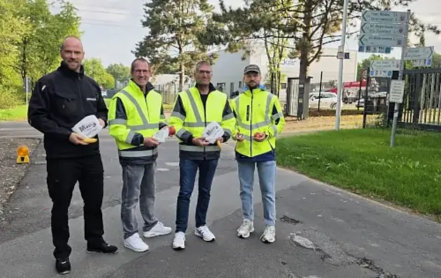 Das Team der Aktion "Pendlerfrühstück": v.l. Dennis Schiffer (Ordnungspolizei); Andreas Damm (Bürgermeister); Oliver Brandenstein (Fachbereichsleiter 4 Bürgerdienstleistungen); Jonas Döbel (Klimaschutzmanager Gemeinde Fuldabrück) stehen in Warnjacken an der Straße und halten Brezeln und Äpfel in der Hand