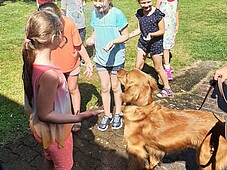 Kinder unter eine Wassfontäne. Daneben steht ein Hunde der Hundestaffel