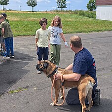 Foto der Kinder mit einem Hundeführer und dessen Hund