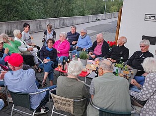 Gruppenbild: TeilnehmerInnen sitzen vor der Pension am offenen Abend