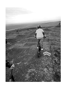 Schwarz-/Weißfoto eines Kindes auf einem BMX auf dem Pumptrack