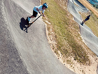 Jugendliche mit Rollern auf dem Pumptrack
