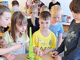 Mehrere Kinder an der Buttonmaschine