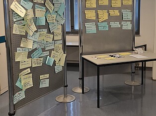Foto der Pinnwand nach der Veranstaltung. Die Pinnwand ist gefüllt mit Zetteln
