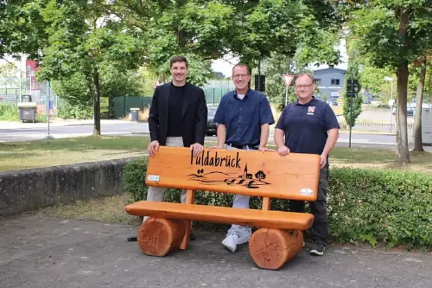 Am Tag der Übergabe der Sitzbank: v.l. Christof Mühling (EAM), Andreas Damm (Bürgermeister), Jörg Walter (Bauhofsleiter) stehen hinter der neuen Holzbank vor dem Rathaus
