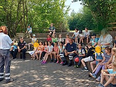 Ein Gruppenfoto der Kinder, sowie der Damen und Herren der Hundestaffel sitzend auf Streintreppen
