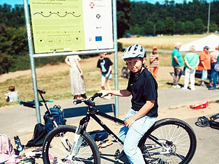 Jugendlicher auf einem BMX vor dem Schild des Pumptracks