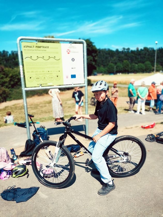 Jugendlicher auf einem BMX vor dem Schild des Pumptracks