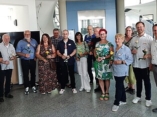 Bürgermeister Andreas Damm mit einiger Besuchern. Alle halten eine Rose in der Hand