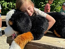 In Mädchen umarmt einen lebensgroßen Stoffhund