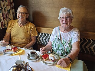 2 TeilnehmerInnen sitzen am Tisch und essen Kuchen