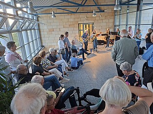 BesucherInnen stehen und sitzen während des Saxophonensembles in der 2. Etage