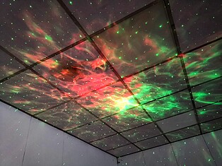 Mit Licht an die Zimmerdecke projezierter Sternenhimmel in rot und grün