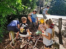 Einige Kinder sitzen auf einem Klettergrüst aus Seilen