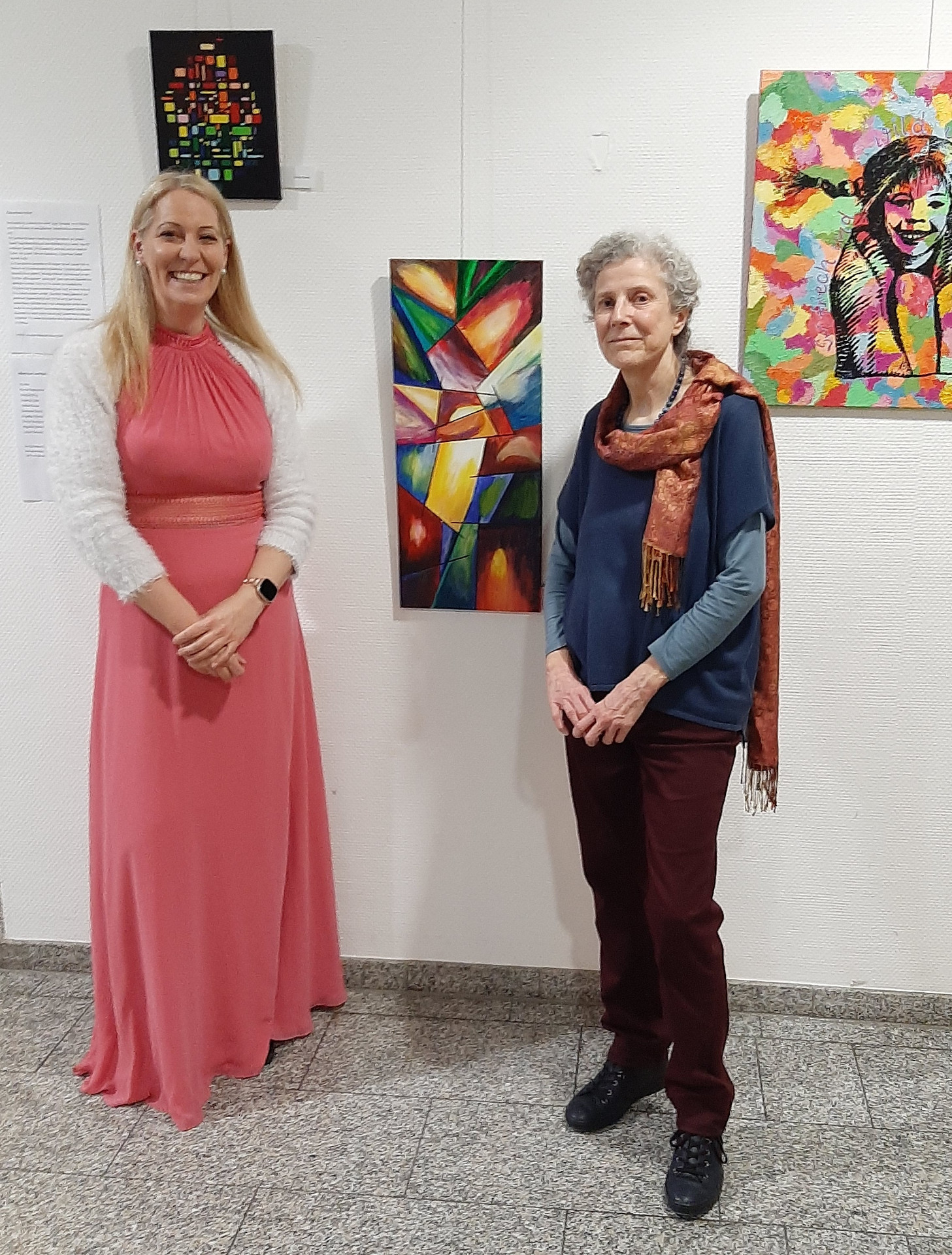 Kulturbeauftragte und Acrylmalkursleitung stehen vor Gemälden