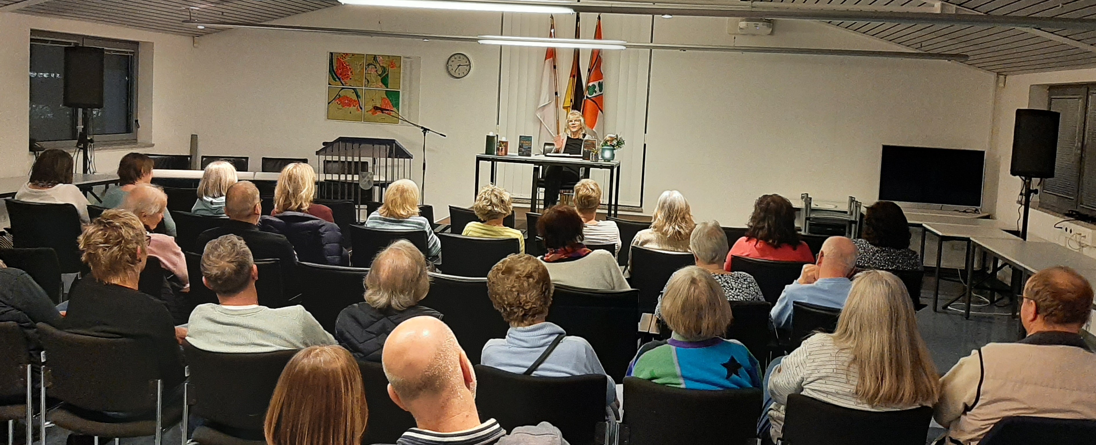 BesucherInnen sitzen im Saal und hören der Lesung zu