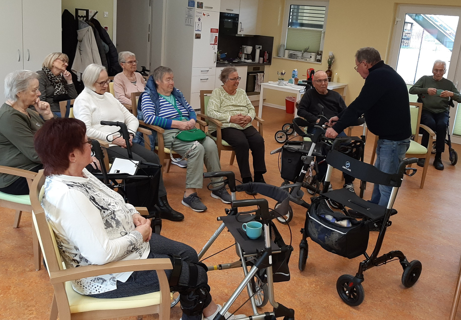 Senioren sitzen auf Stühlen und lauschen Vortrag